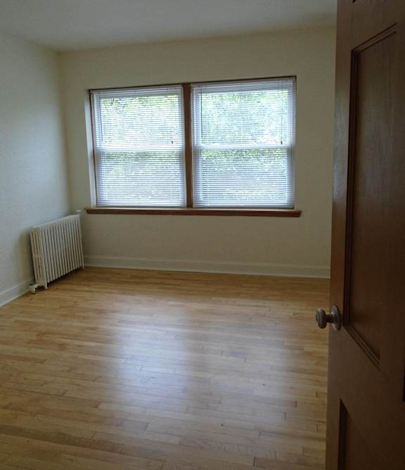 A room with a wooden floor and a window with blinds.