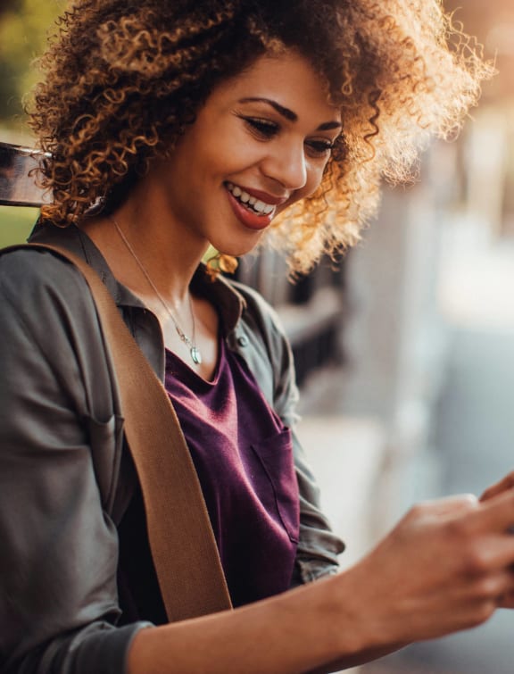 a woman looking at her cell phone while sitting on a bench