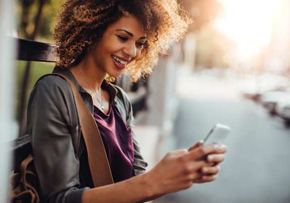 A woman with curly hair is looking at her phone.