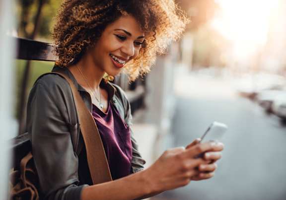 A woman with curly hair is looking at her phone.