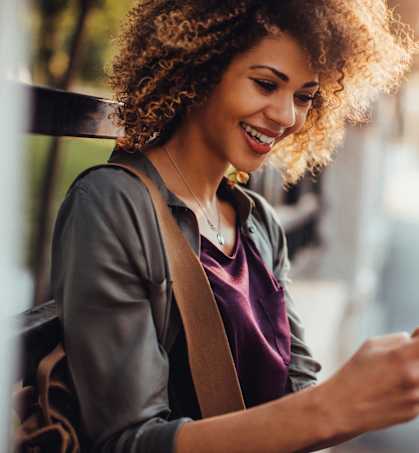 a woman looking at her cell phone while sitting on a bench