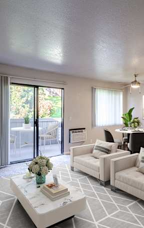 A living room with a white couch, a coffee table, and a mirror on the wall.