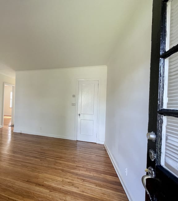 an empty living room with wood floors and white walls