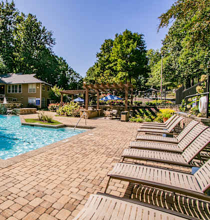 A pool surrounded by trees and a gazebo.