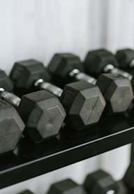 A set of hexagonal dumbbells are arranged on a shelf.