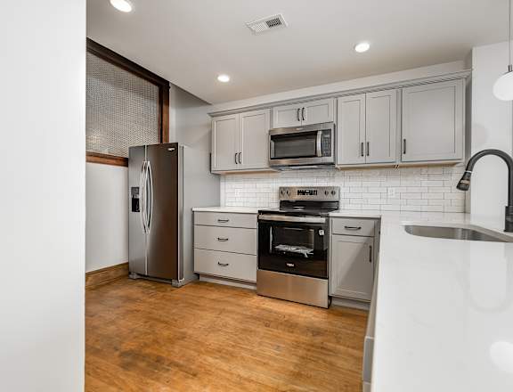 A modern kitchen with wooden floors and stainless steel appliances.