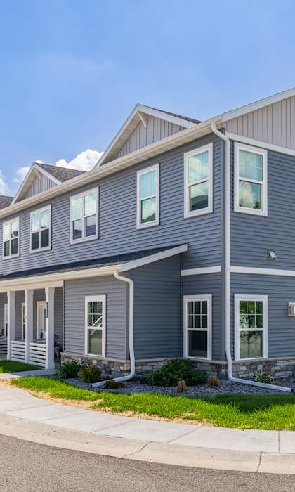 A row of houses with grey siding and white trim.