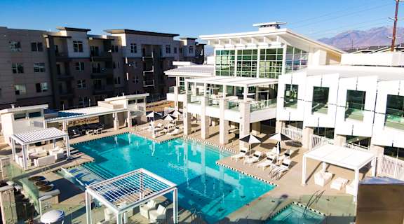 A large swimming pool surrounded by lounge chairs and umbrellas.