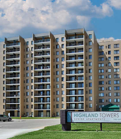 The Highland Towers senior apartment complex is a large building with a sign in front of it.