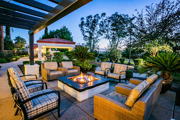 A patio with a fire pit and chairs.