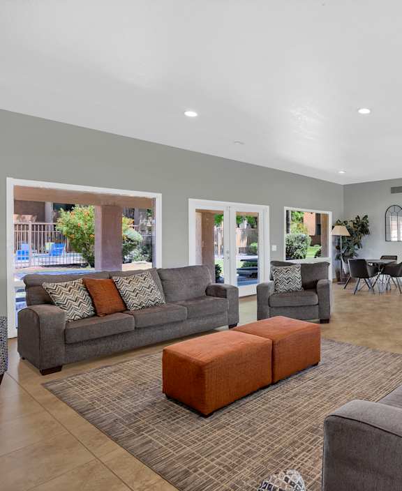 A spacious living room with grey couches and a brown rug.