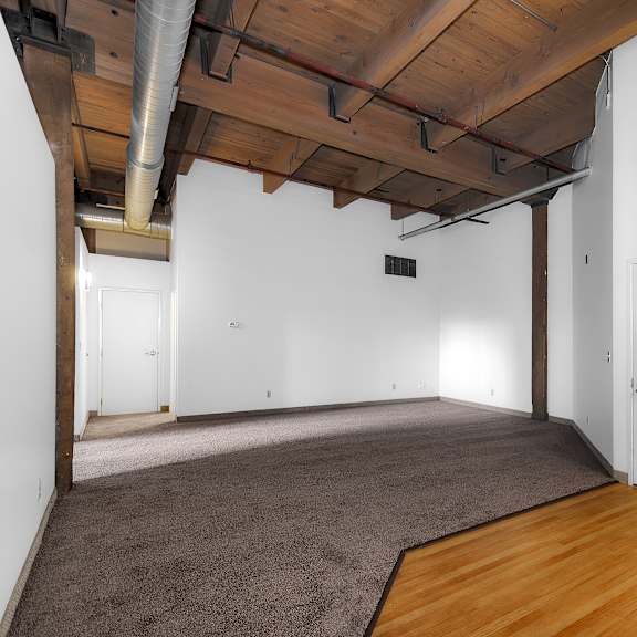 Open loft space with exposed wood ceiling beams at Off Broadway Apartments