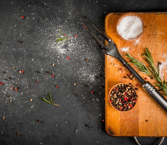 a wooden cutting board with spices and knives on a table