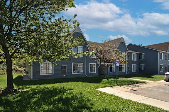 Two-story apartment building with trees and a lawn at Garfield Commons in Clinton Township, MI
