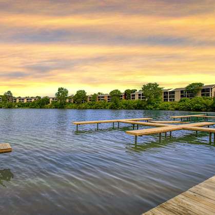 A serene lake with wooden benches and a sunset sky.