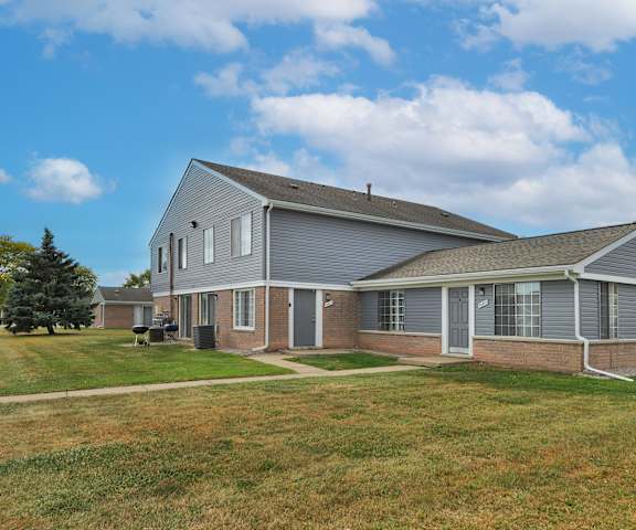 A house with a grey roof and a green lawn in front.