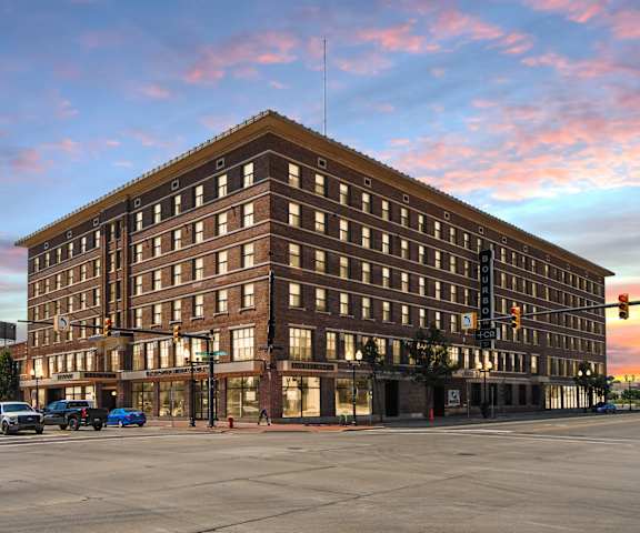 a tall building on the corner of a street at sunset