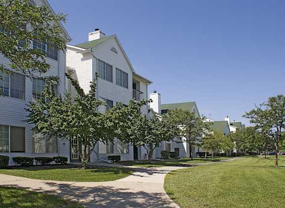 a row of white houses with trees and a sidewalk at Village Club on Franklin, Southfield Michigan