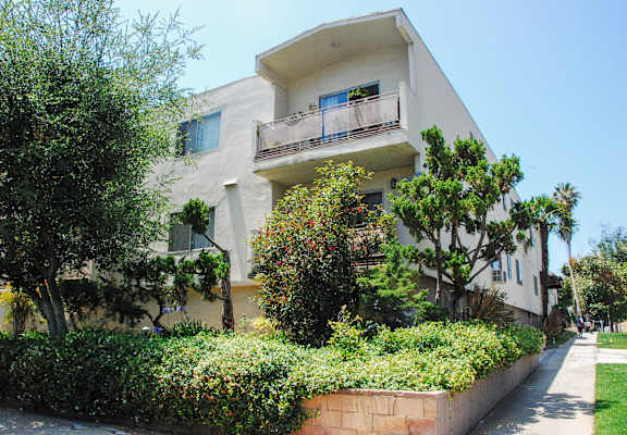 A white two-story building with a balcony on the second floor.