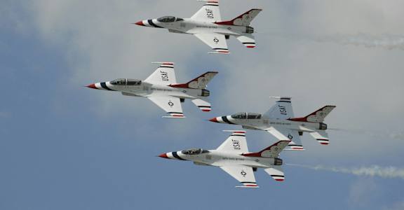 four fighter jets flying in formation in the sky
