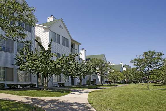 a row of white houses with trees and a sidewalk at Village Club on Franklin, Southfield, MI 48034