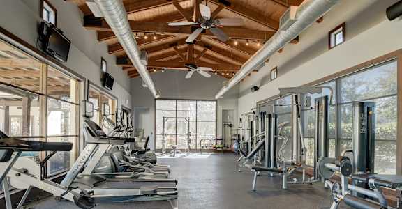 A gym with treadmills, elliptical machines, and a fan.