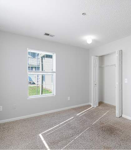 A spacious room with a large window and carpeted floor.