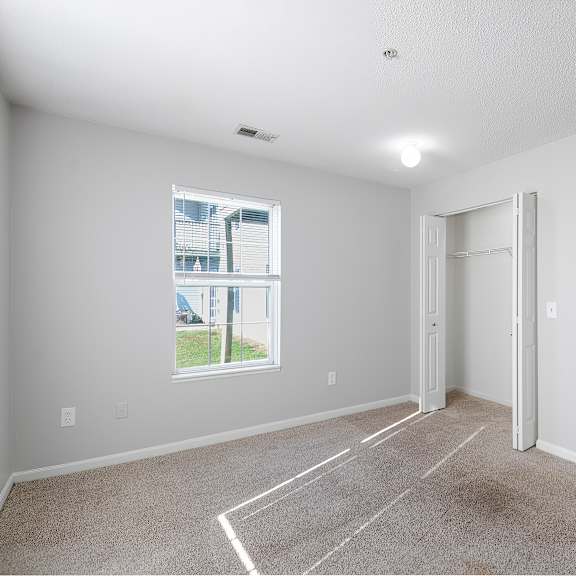 Carpeted bedroom with a window and closet at Hunters Ridge in Kalamazoo, MI