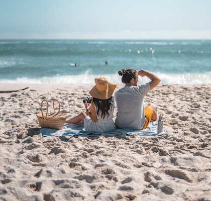 A couple is sitting on the beach, enjoying the view of the ocean.