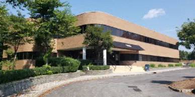 an office building with a parking lot and trees