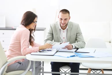 two people sitting at a table looking at a piece of paper