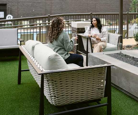 Two women sitting on a patio with white furniture at Anthem House, Alabama