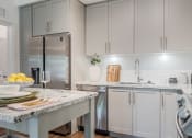 Thumbnail 2 of 35 - a kitchen with white cabinets and marble countertops at The Lotus at Village Walk, Fort Myers, Florida