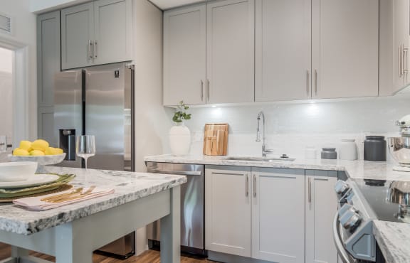 a kitchen with white cabinets and marble countertops at The Lotus at Village Walk, Fort Myers, Florida