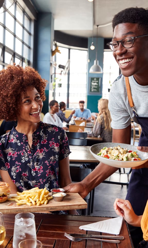 a group of people sitting around a table eating food at a restaurant