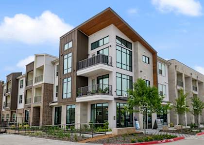 A large apartment complex with a parking lot in front.