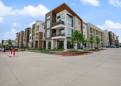 A large apartment complex with a parking lot in front.