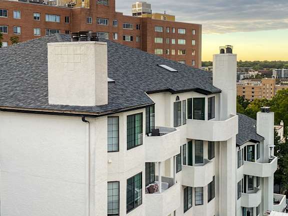 A white building with a black roof and a chimney.