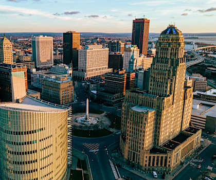 A cityscape with a mix of modern and older buildings, a river in the background, and a clear sky.