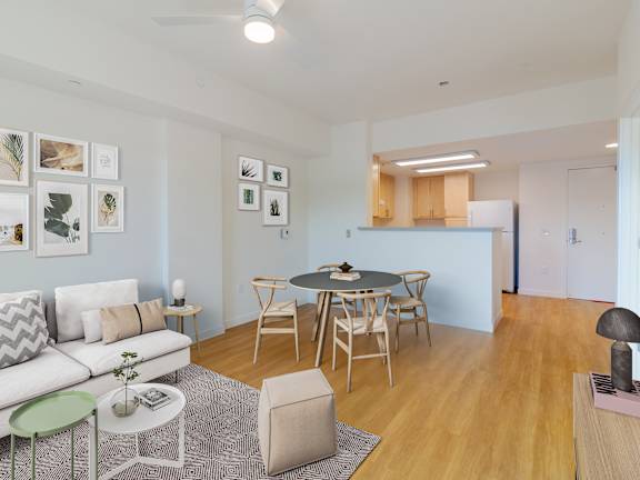 A living room with a white couch, a dining table with chairs, and pictures on the wall.