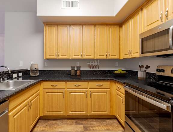 A kitchen with wooden cabinets and black countertops.