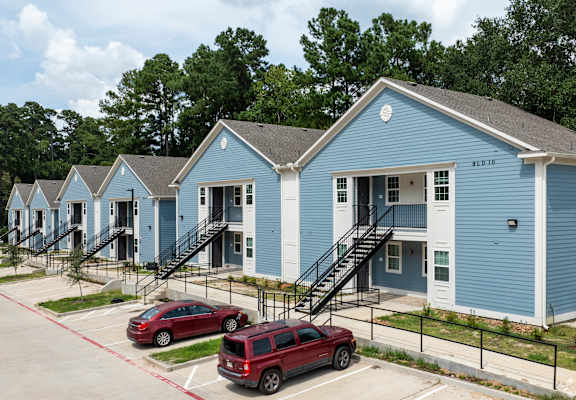 a row of blue houses with cars parked in front of them