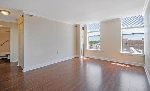 Living room with hardwood floors and large windows at Bancroft Luxury Apartments in Saginaw, MI