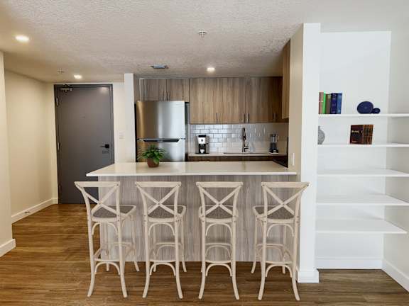a kitchen with a island and bar stools in a living room  at Palm Gardens @ Biscayne Gardens, North Miami, FL