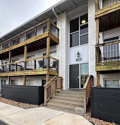 the exterior of an apartment building with stairs and a black fence