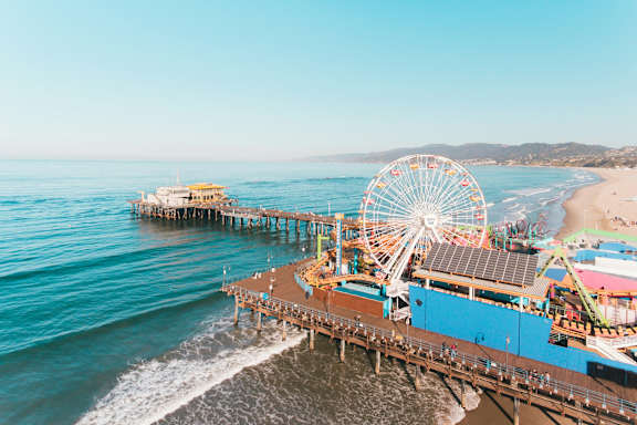 A pier with a ferris wheel and a building with solar panels on the roof.