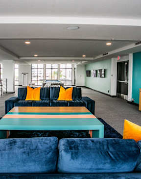 A blue velvet couch with yellow pillows in a bright room.