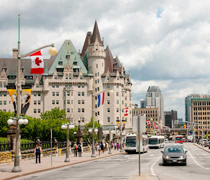 A street scene with a large building in the background and cars driving on the road.
