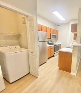 A living space with a kitchen and wood floors and washer and dryer