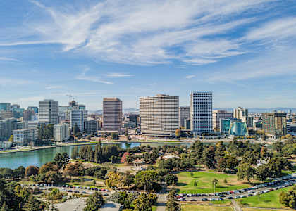 A cityscape with a river and greenery in the foreground.
